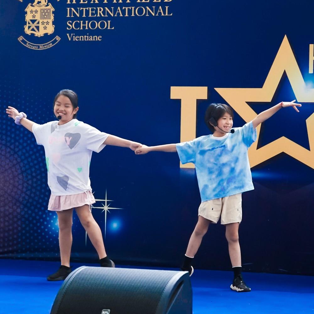 Two students hold hands and perform a coordinated dance.