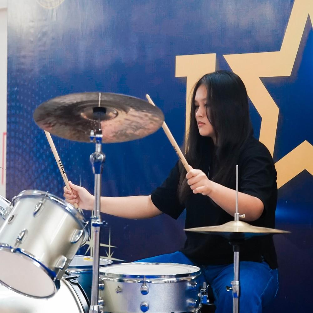 Girl drummer gives an energetic drum performance as part of a rock band band.
