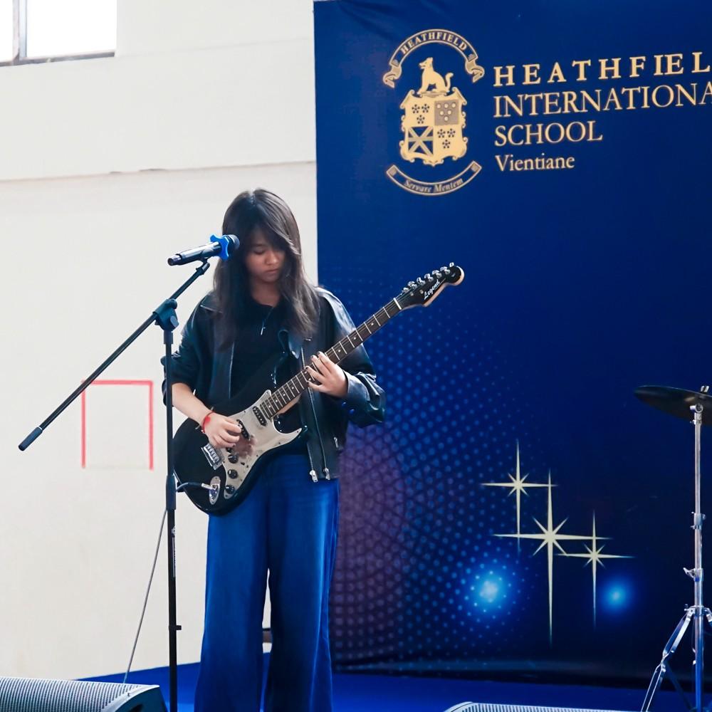 Girl guitarist playing with her band during a live talent show act.