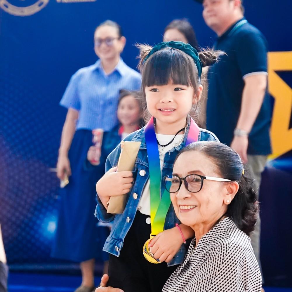 Girl poses with a first place medal alongside a family member after the talent show.