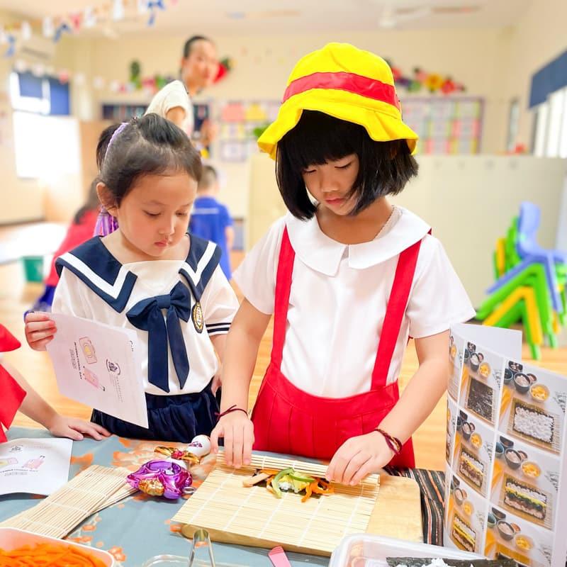 Two students in Japanese costumes preparing a sushi roll activity.