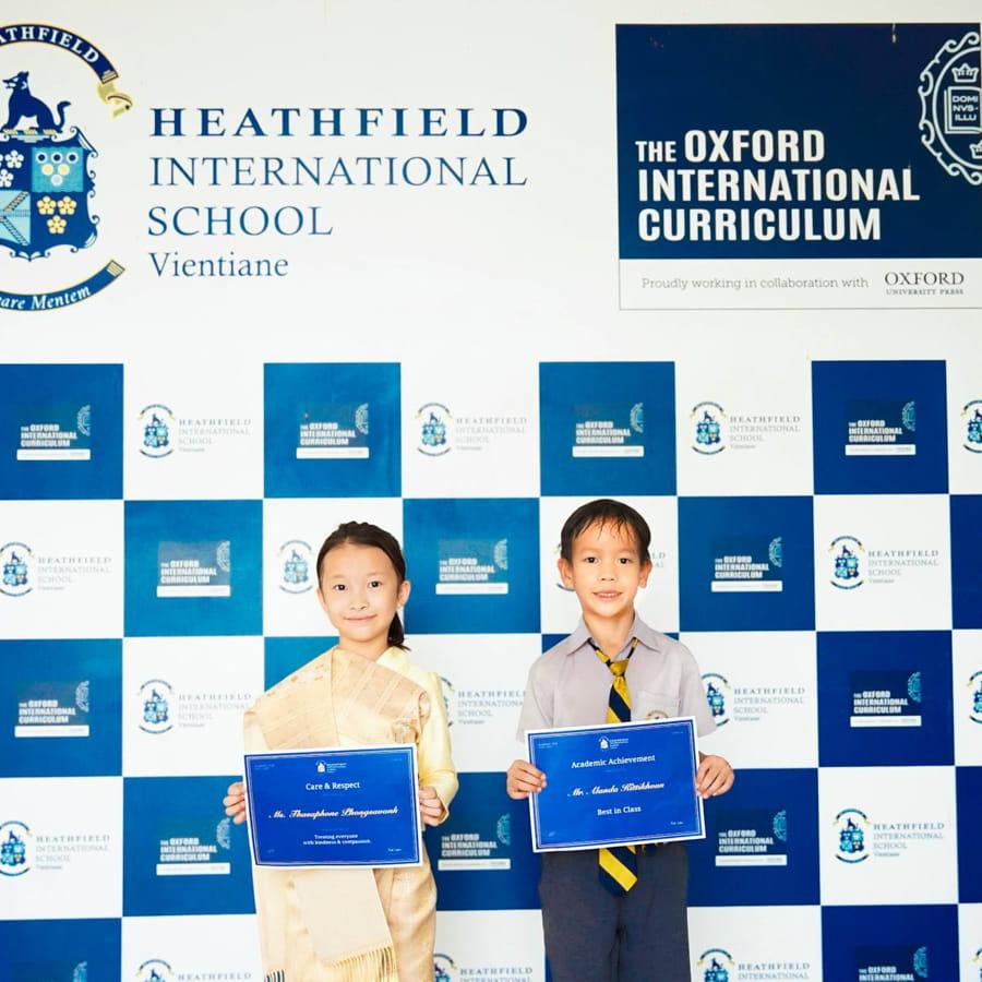 Two students smiling and holding achievement certificates
