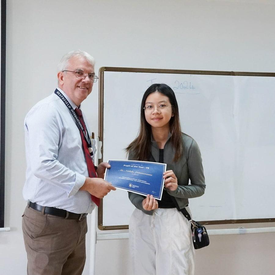 School headmaster giving a certificate of achievement to a student