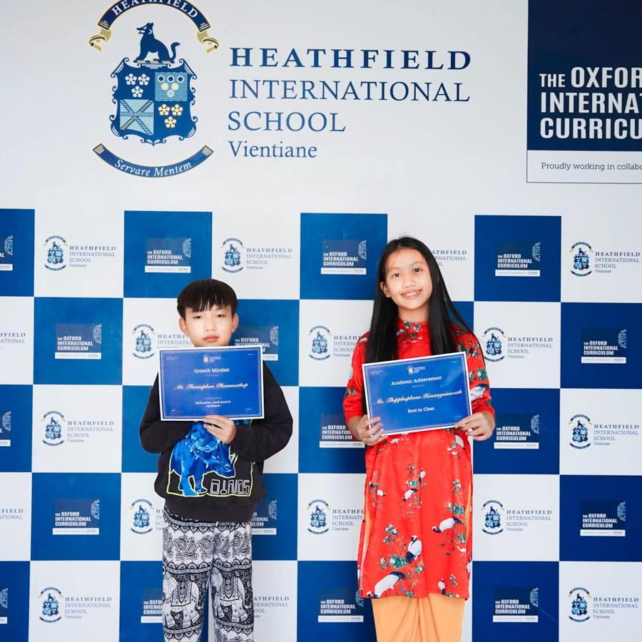 Two students smiling and holding achievement certificates