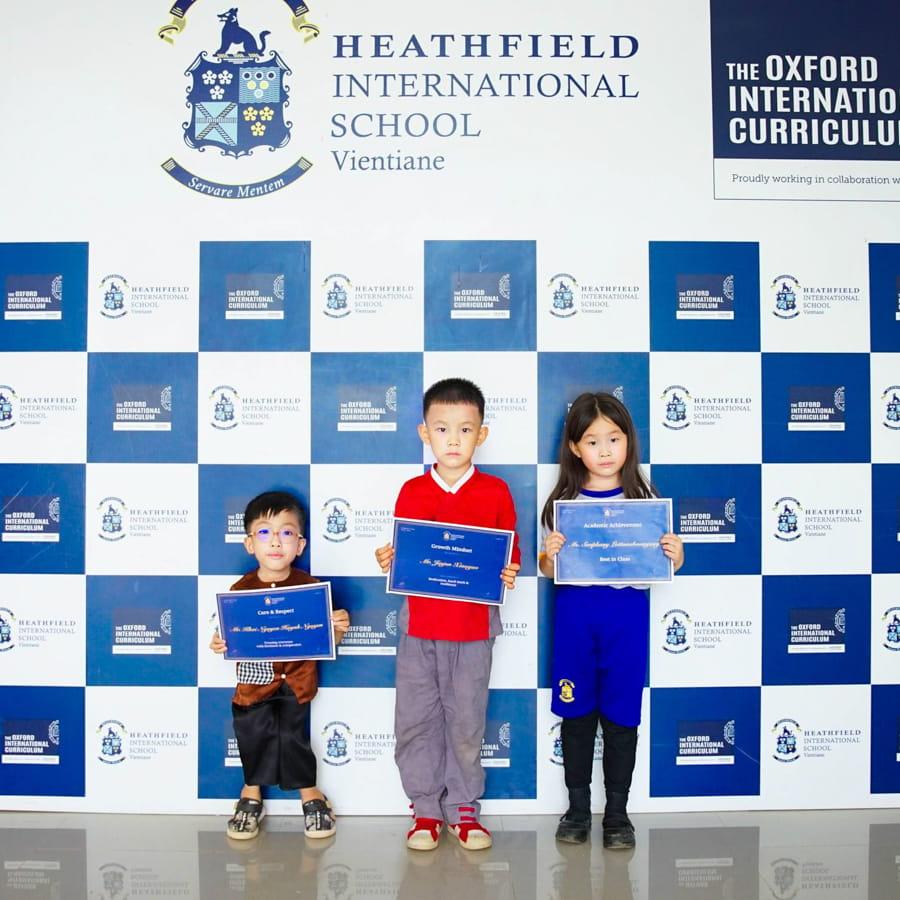 Three students smiling and holding achievement certificates