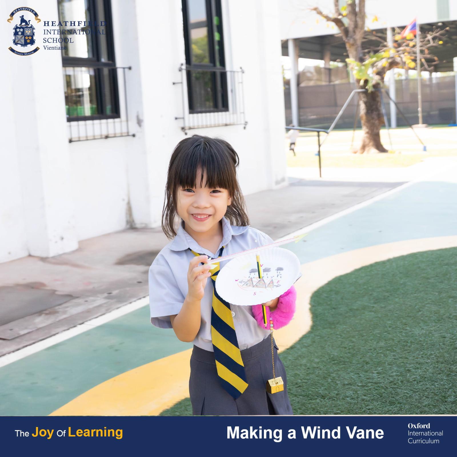 A student proudly holding a handmade wind vane created during a science lesson at Heathfield International School.