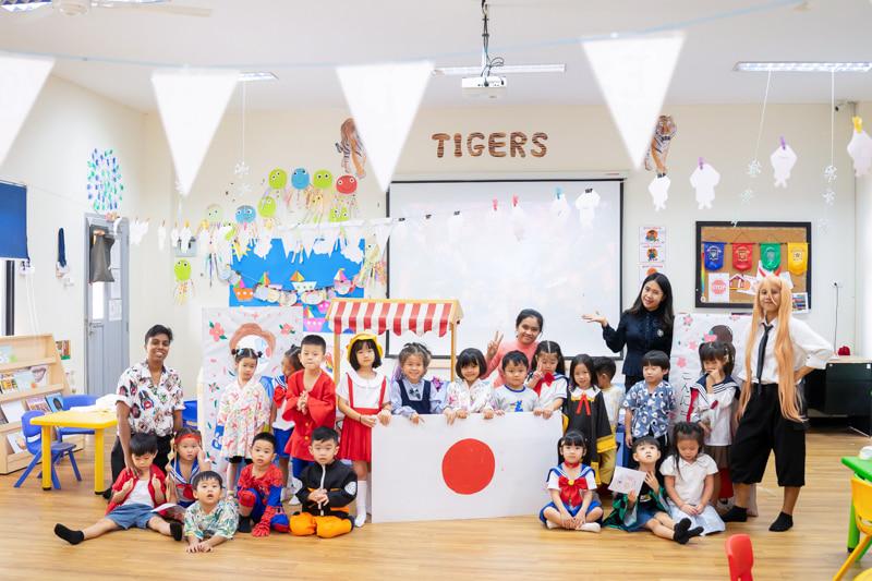Students and teachers dressed in Japanese themed costumes, holding a Japanese flag