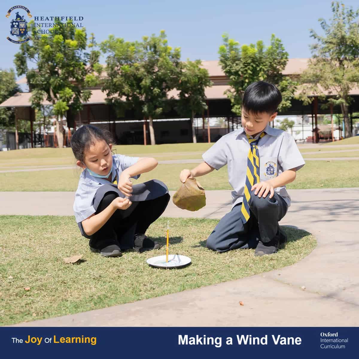Two students working together outdoors to assemble their wind vane using simple materials.