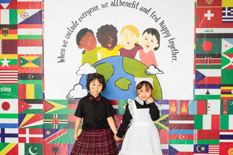 Two young students representing Germany, holding hands in front of an international day backdrop